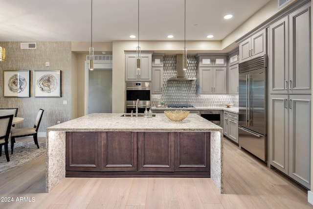 kitchen featuring hanging light fixtures, light hardwood / wood-style floors, light stone countertops, and stainless steel appliances