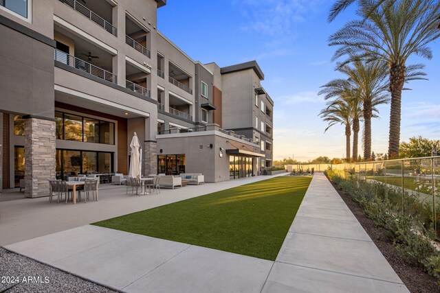 pool at dusk with a water view and a patio area