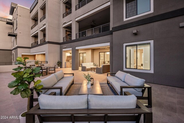 patio terrace at dusk with outdoor lounge area, a balcony, and ceiling fan