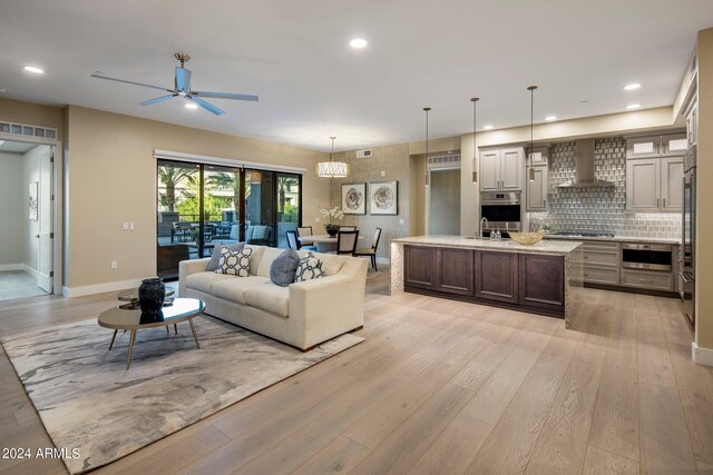 living room featuring light hardwood / wood-style flooring, ceiling fan, and sink