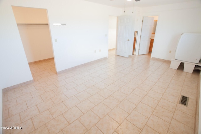 unfurnished room featuring ceiling fan, washer / clothes dryer, and light tile patterned floors