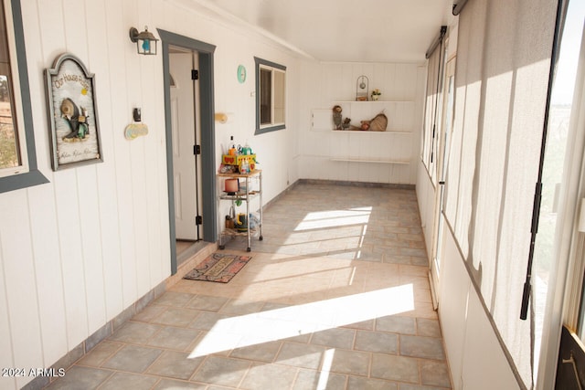 hall featuring ornamental molding and wooden walls