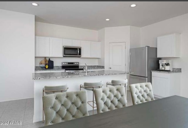 kitchen featuring light stone countertops, appliances with stainless steel finishes, and white cabinetry