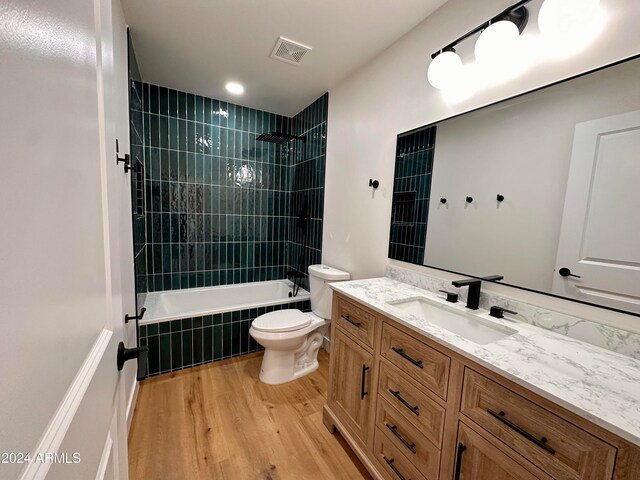 full bathroom featuring vanity, tiled shower / bath, hardwood / wood-style floors, and toilet