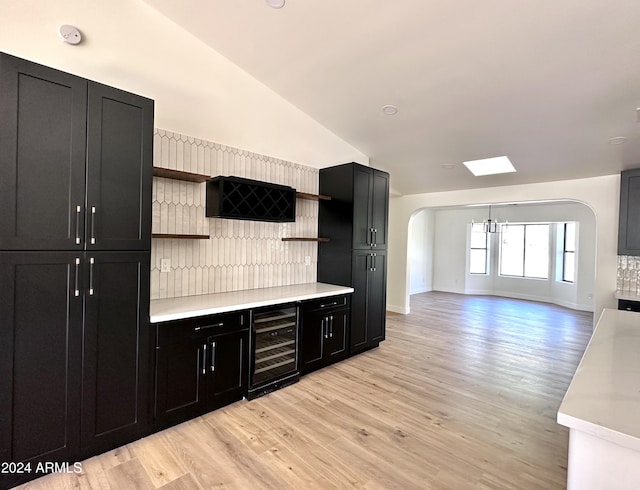 kitchen featuring light hardwood / wood-style flooring, lofted ceiling, a chandelier, and beverage cooler