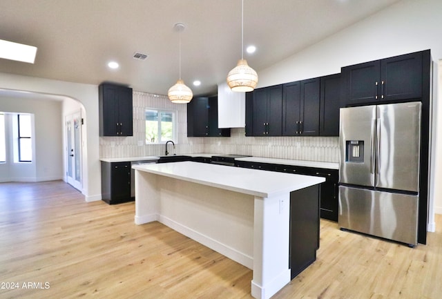 kitchen with pendant lighting, a kitchen island, stainless steel appliances, and light hardwood / wood-style floors