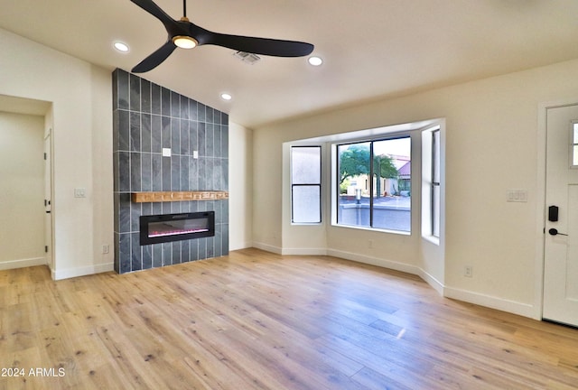 unfurnished living room featuring light hardwood / wood-style flooring, lofted ceiling, a fireplace, and ceiling fan