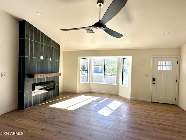 unfurnished living room featuring vaulted ceiling, a fireplace, wood-type flooring, and ceiling fan