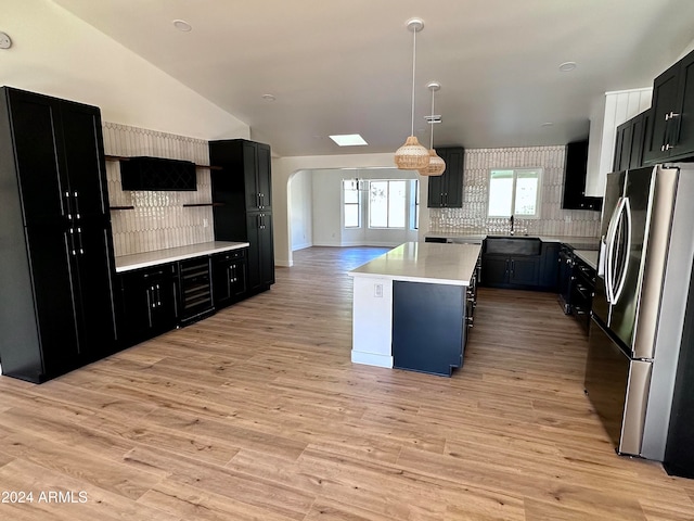 kitchen with light wood-type flooring, stainless steel refrigerator, a center island, and pendant lighting