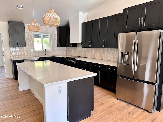 kitchen featuring sink, a center island, pendant lighting, appliances with stainless steel finishes, and light hardwood / wood-style floors