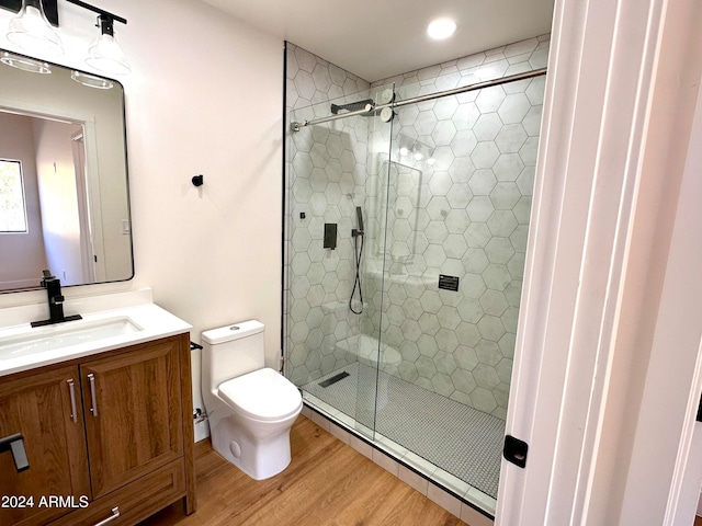 bathroom with toilet, a shower with shower door, hardwood / wood-style floors, and vanity