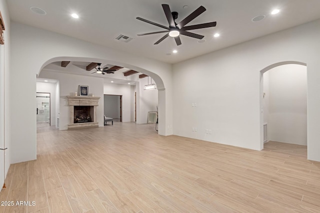 unfurnished living room with beam ceiling, ceiling fan, and light hardwood / wood-style floors