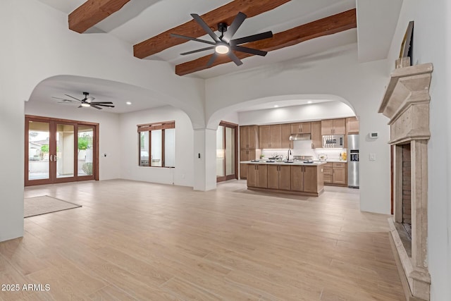 unfurnished living room featuring beamed ceiling, french doors, light hardwood / wood-style floors, and ceiling fan