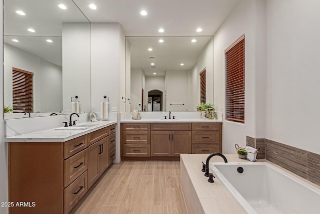 bathroom with vanity and tiled tub