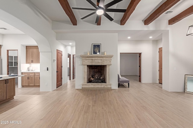 unfurnished living room featuring beamed ceiling, light wood-type flooring, and ceiling fan