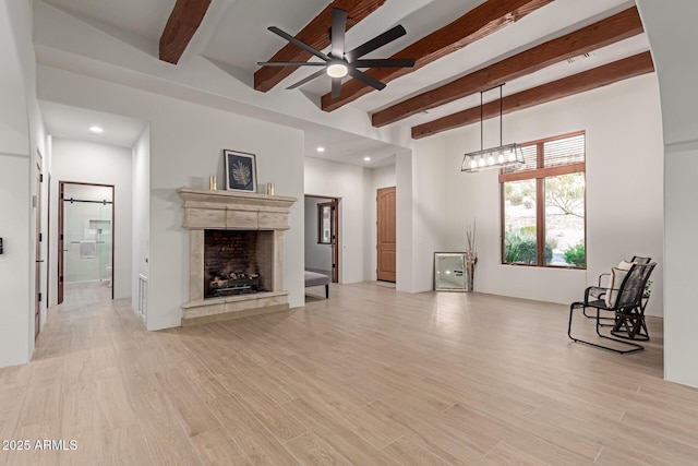 unfurnished living room featuring ceiling fan, beamed ceiling, and light hardwood / wood-style floors