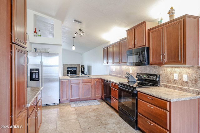 kitchen featuring black appliances, a tile fireplace, sink, backsplash, and lofted ceiling