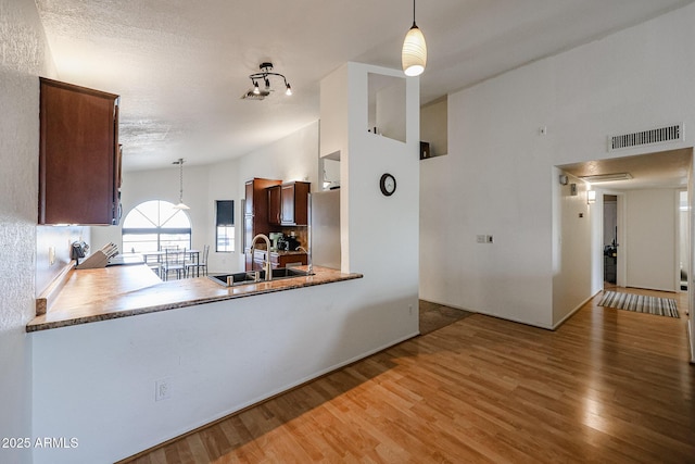 kitchen with sink, hardwood / wood-style flooring, pendant lighting, and stainless steel fridge