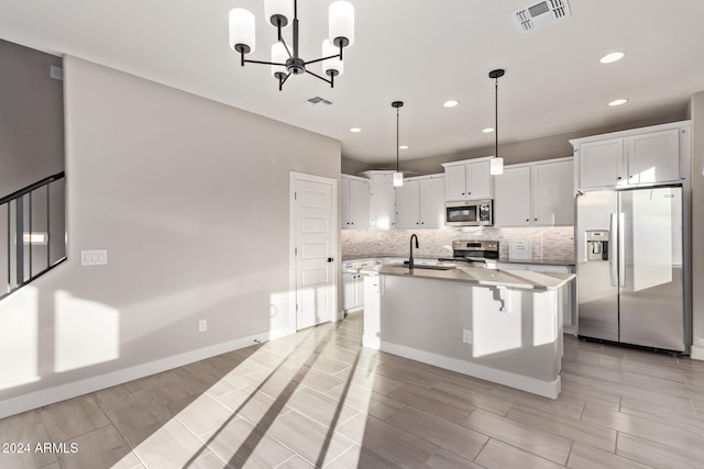 kitchen with stainless steel appliances, sink, a kitchen island with sink, white cabinets, and pendant lighting