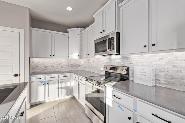 kitchen with backsplash, white cabinets, and stainless steel appliances