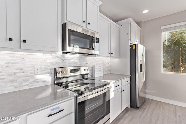 kitchen featuring light hardwood / wood-style floors, white cabinetry, appliances with stainless steel finishes, and tasteful backsplash