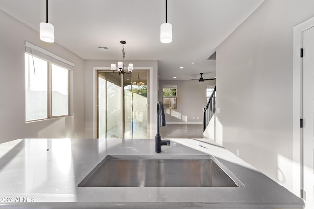 kitchen with hanging light fixtures, sink, and ceiling fan with notable chandelier