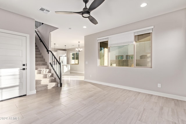 unfurnished room featuring ceiling fan with notable chandelier and light hardwood / wood-style flooring