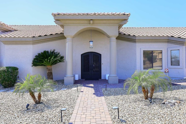 property entrance featuring a tiled roof, stucco siding, and french doors