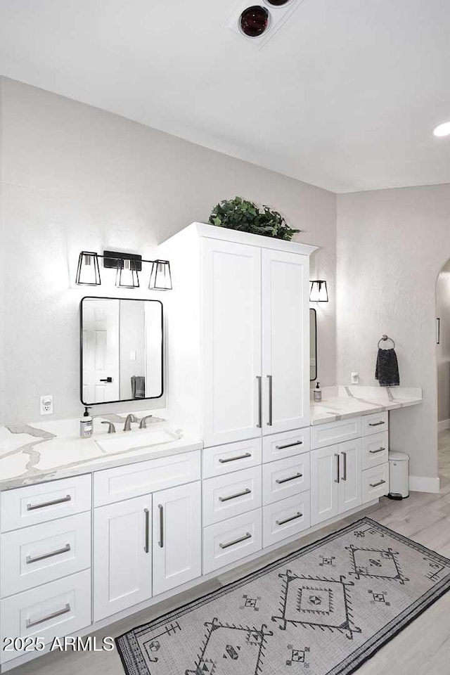 bathroom featuring a sink, baseboards, wood finished floors, and double vanity