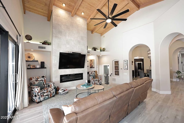 living area featuring visible vents, wood ceiling, light wood-style flooring, and a tiled fireplace