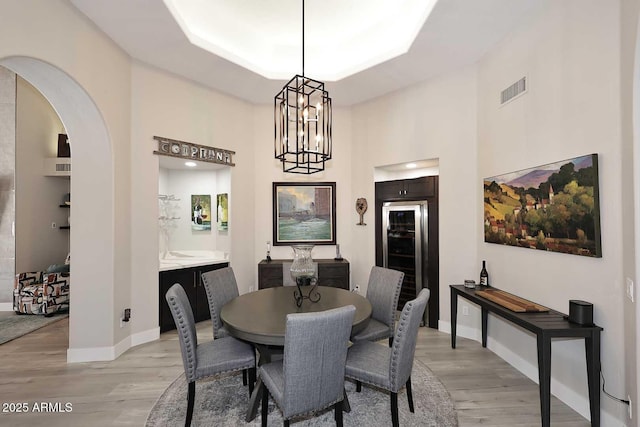 dining space featuring wine cooler, baseboards, visible vents, and light wood-type flooring