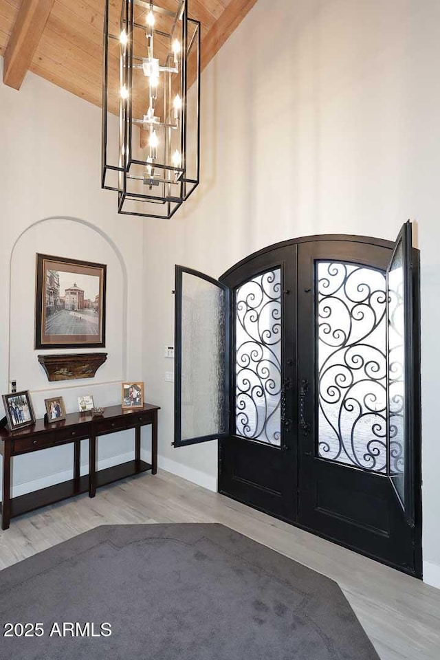 foyer entrance featuring beamed ceiling, high vaulted ceiling, french doors, an inviting chandelier, and wood ceiling