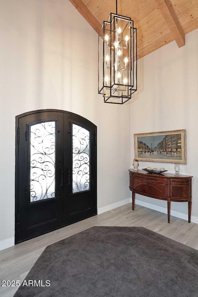 entryway featuring baseboards, beam ceiling, wooden ceiling, french doors, and wood finished floors