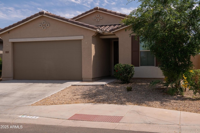 view of front of home featuring concrete driveway, stucco siding, a tiled roof, and an attached garage