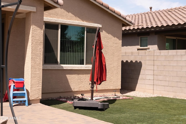 view of home's exterior featuring fence, a patio, stucco siding, and a tiled roof