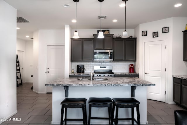 kitchen featuring a breakfast bar area, visible vents, a sink, backsplash, and stainless steel appliances