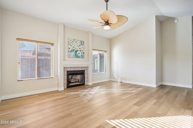 unfurnished living room with ceiling fan, light hardwood / wood-style floors, lofted ceiling, and a tiled fireplace