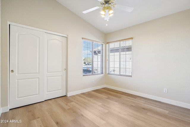 unfurnished bedroom with vaulted ceiling, a closet, light hardwood / wood-style flooring, and ceiling fan