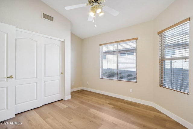 unfurnished bedroom featuring light hardwood / wood-style floors, a closet, lofted ceiling, and ceiling fan