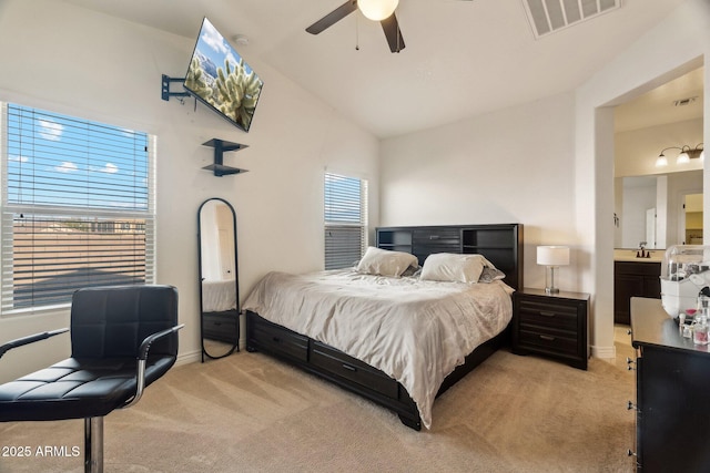 bedroom with ceiling fan, ensuite bathroom, vaulted ceiling, and light carpet