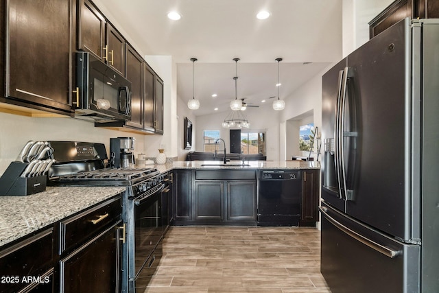 kitchen featuring sink, light wood-type flooring, kitchen peninsula, pendant lighting, and black appliances