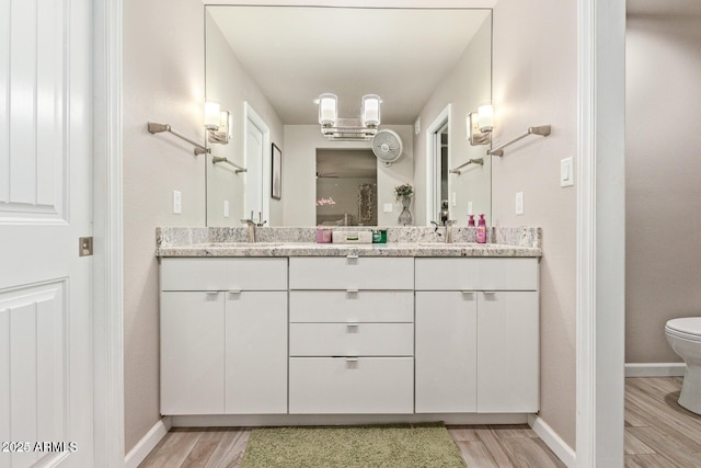 5913 E Thomas Rd, Scottsdale, AZ 85251 - bathroom featuring double vanity, wood finished floors, toilet, and baseboards