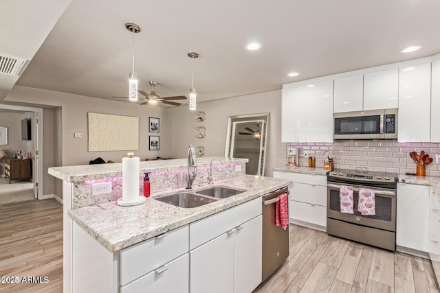 5913 E Thomas Rd, Scottsdale, AZ 85251 - kitchen with stainless steel appliances, a sink, a ceiling fan, a center island with sink, and backsplash