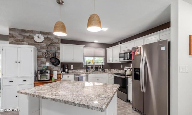 kitchen featuring appliances with stainless steel finishes, white cabinetry, a center island, and hanging light fixtures