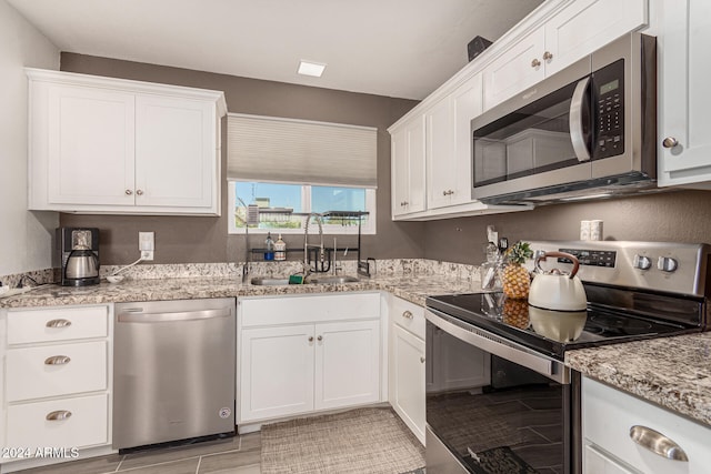 kitchen featuring light stone countertops, sink, stainless steel appliances, white cabinets, and light hardwood / wood-style flooring