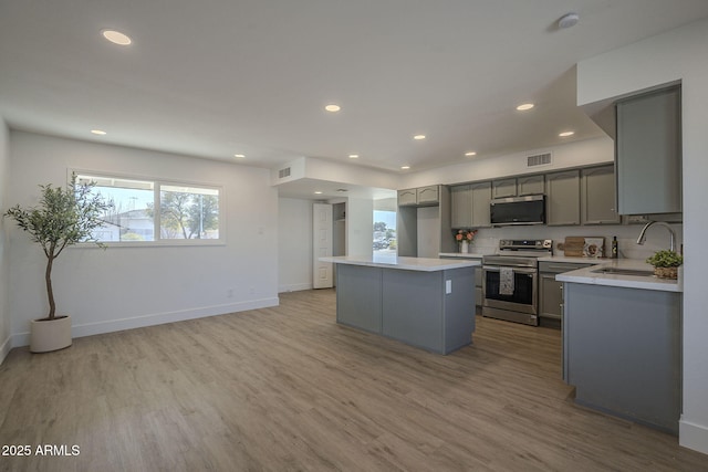 kitchen featuring sink, gray cabinetry, stainless steel appliances, a center island, and light hardwood / wood-style floors