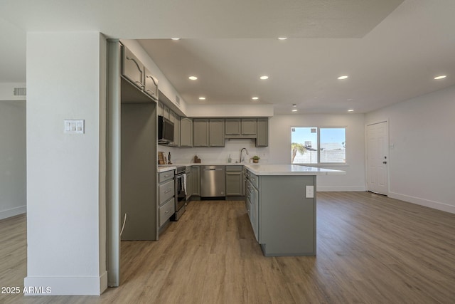 kitchen with sink, gray cabinets, stainless steel appliances, and light wood-type flooring