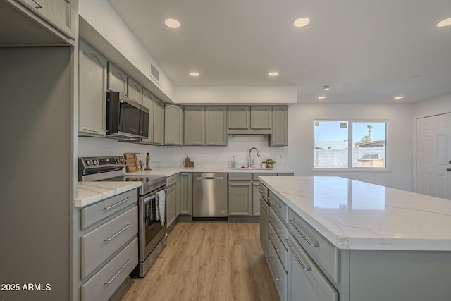 kitchen featuring gray cabinets, appliances with stainless steel finishes, sink, light stone countertops, and light hardwood / wood-style flooring