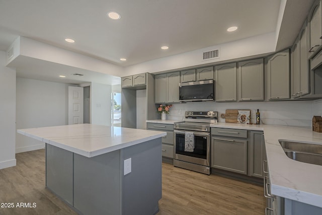 kitchen with sink, gray cabinets, appliances with stainless steel finishes, a center island, and wood-type flooring