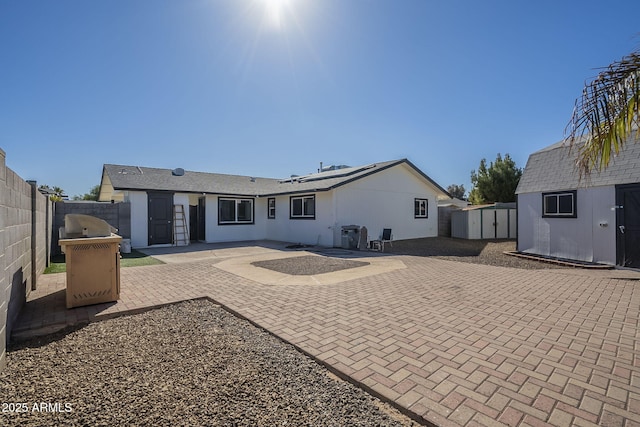 back of house with a storage shed and a patio area